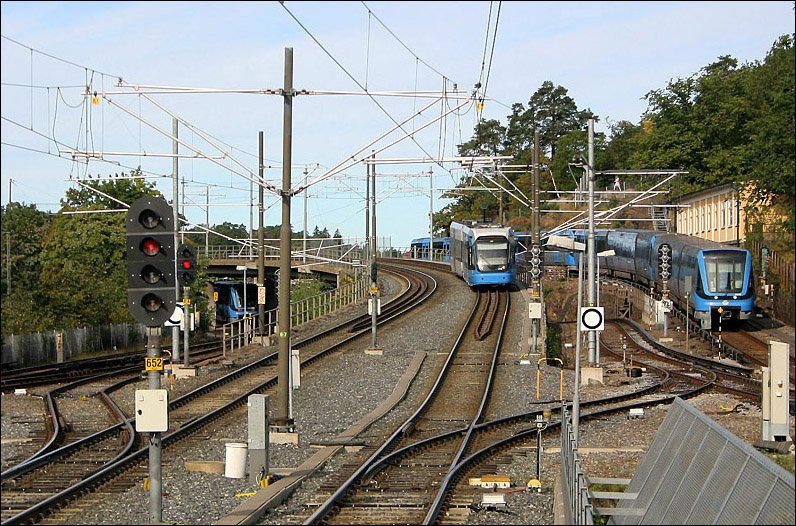 Alvik, Grne Linie, T17, T18, T19. Blick nach Westen auf den Gleisbereich in Richtung Stora mossen bzw Nockeby. Das mittlere Gleispaar wird von der Nockebybahn befahren. Die beiden ueren Gleise sind die Streckengleise der U-Bahn. Dazwischen fhren noch Gleise zum Betriebshof der U-Bahn und der Nockebybahn. Diese sind daher sowohl mit Stromschienen als auch mit Oberleitungen versehen. ber diese Gleise wendet auch die Linie T17 der U-Bahn auerhalb der HVZ. 29.08.2008 (Matthias)
